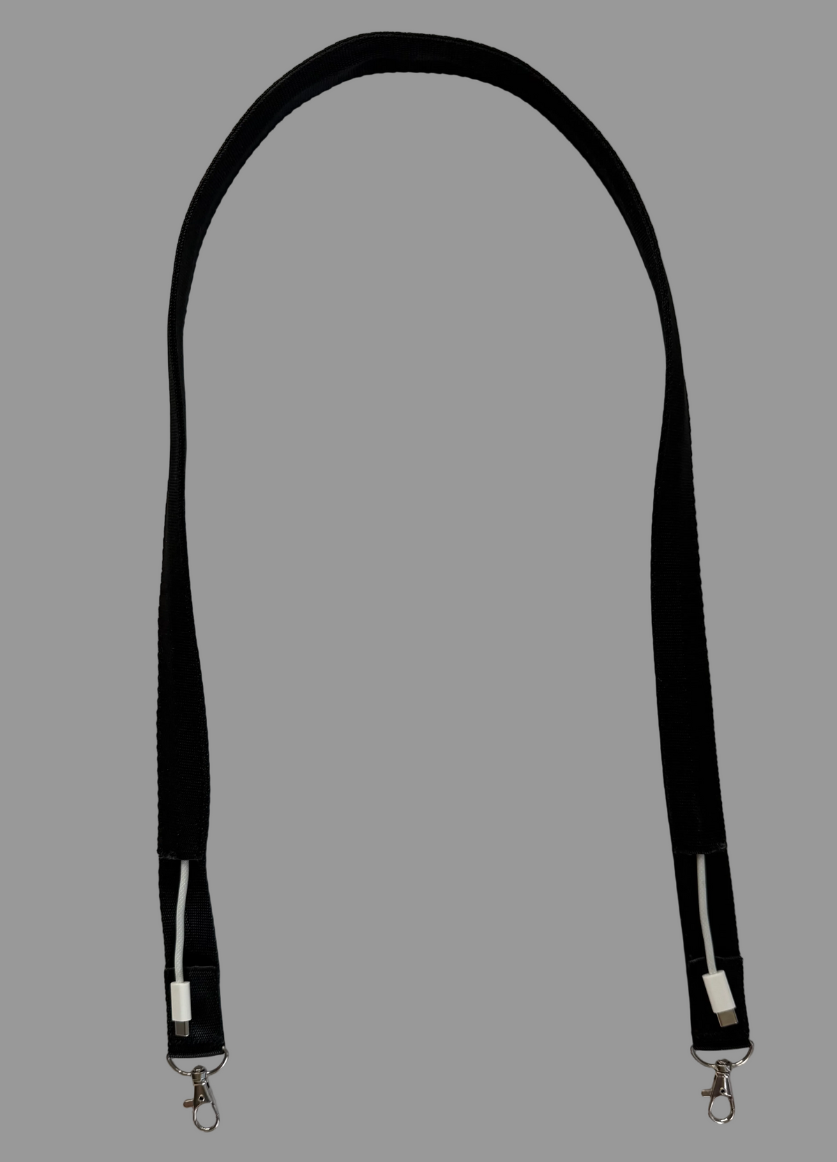A black fabric strap with silver metal lobster clasps on both ends, laid flat on a white tiled surface.